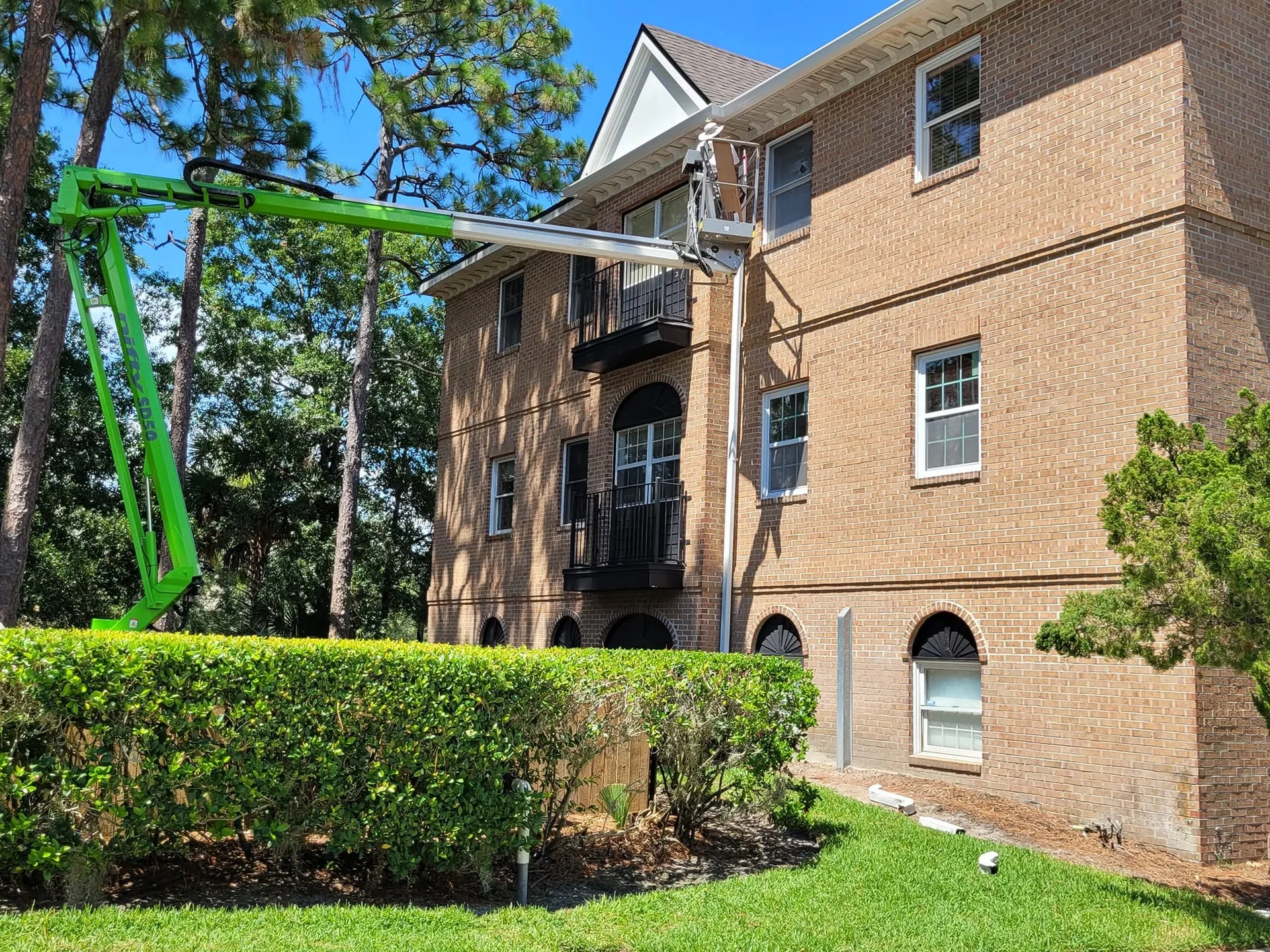 Green boom lift three story brick home white gutter eave, Lake Mary